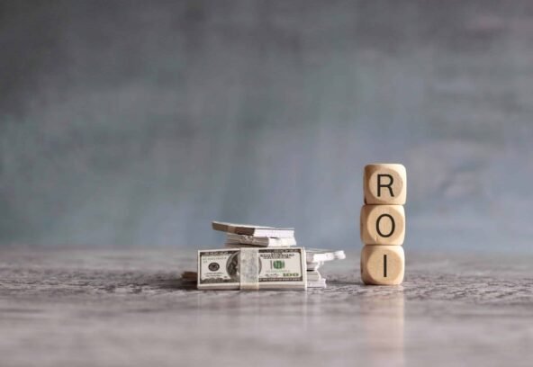 Stack of money and wooden cubes with text ROI. Return On Investment, financial and business concept